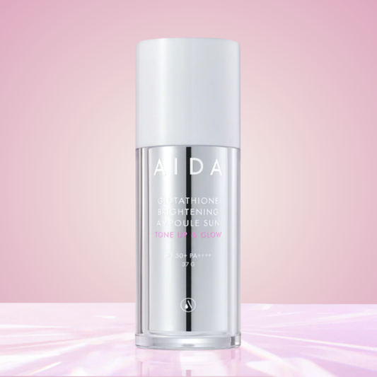 AIDA Glutathione Brightening Ampoule Sun displayed on glossy pink surface – luminous tone-up sunscreen