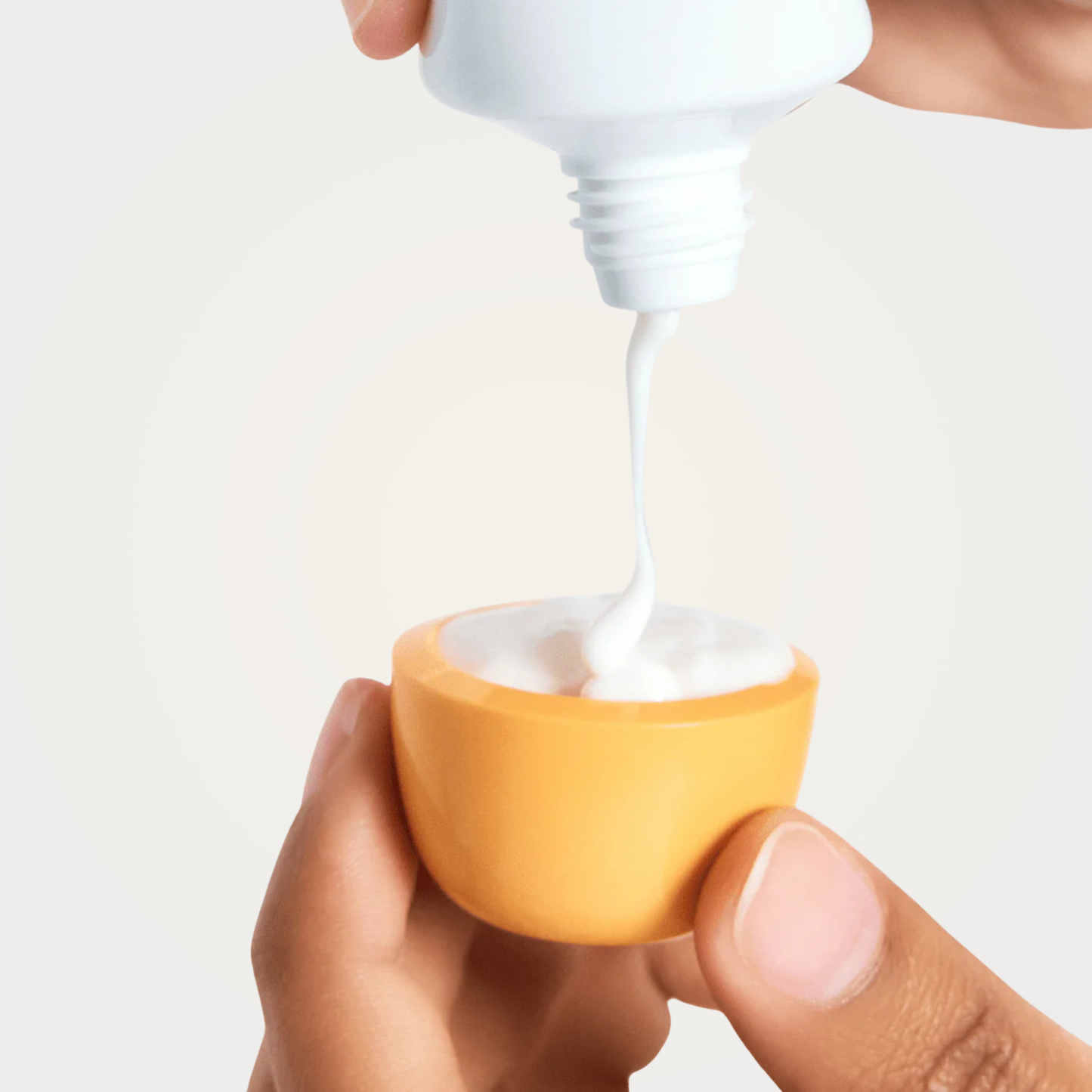 Anua Zero-Cast Moisturizing Finish Sunscreen pouring, showing creamy fluid texture.