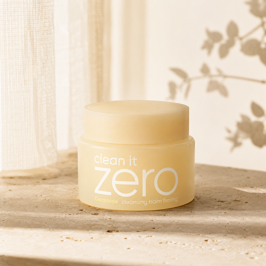 Banila Co Clean It Zero Ceramide Cleansing Balm Firming displayed on warm travertine with soft morning light in a premium Korean skincare hero photo.