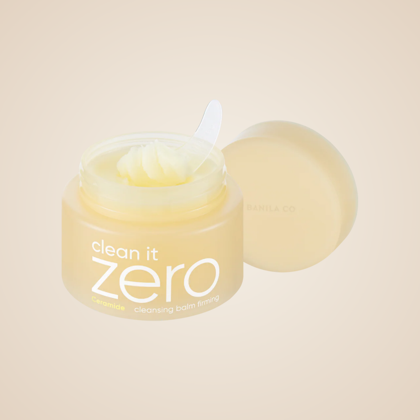 Open jar of Banila Co Clean It Zero Ceramide Cleansing Balm with included spatula and creamy balm texture