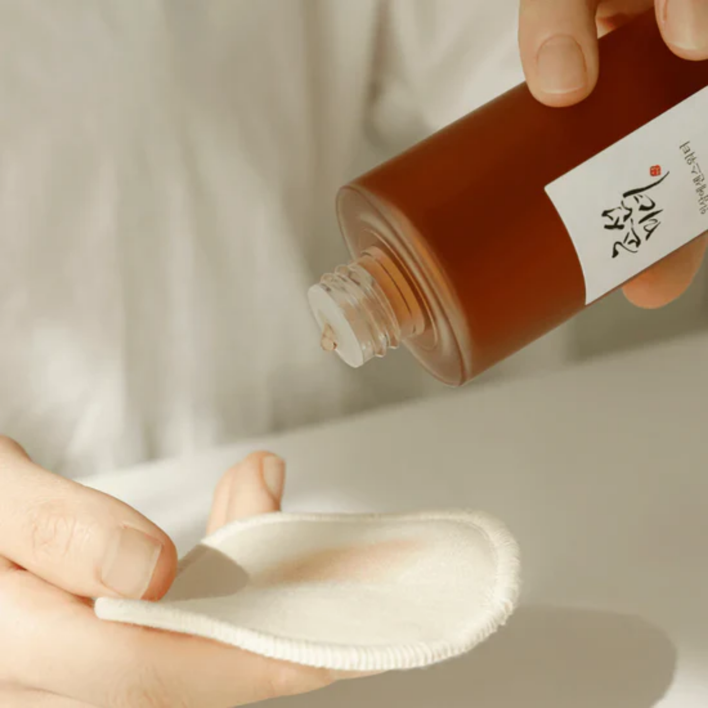 Applying Beauty of Joseon Ginseng Essence Water with cotton pad – restoring glow and skin vitality