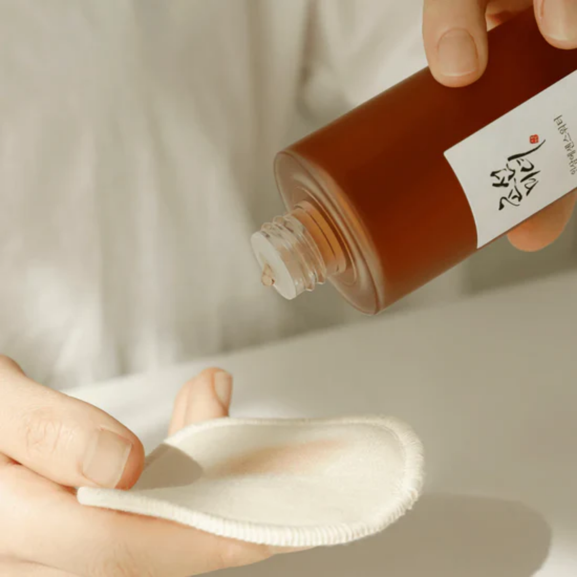 Applying Beauty of Joseon Ginseng Essence Water with cotton pad – restoring glow and skin vitality