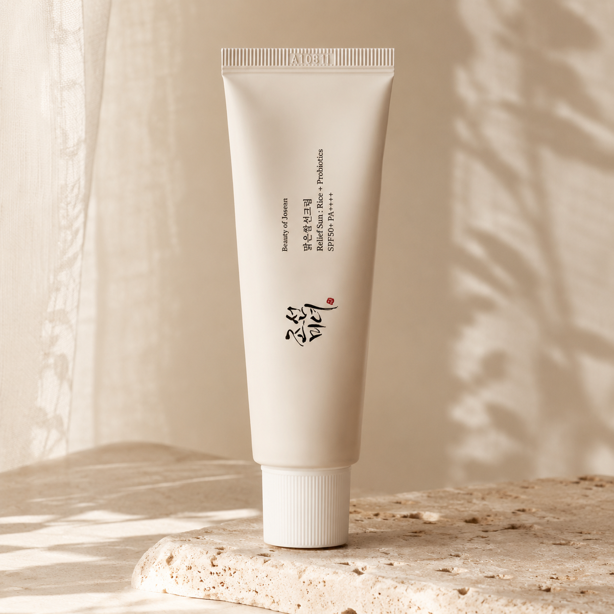 Beauty of Joseon Relief Sun Rice + Probiotics SPF50+ PA++++ 50ml standing on warm ivory travertine with soft morning sunlight and minimal botanical shadows in a luxury Korean skincare hero photo.
