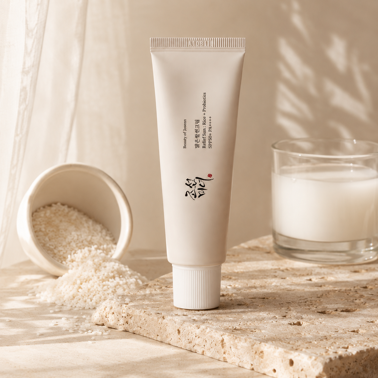 Beauty of Joseon Relief Sun Rice + Probiotics SPF50+ PA++++ 50ml displayed with rice-inspired ingredients on warm travertine, highlighting its rice and probiotic skincare formula in a premium editorial composition.