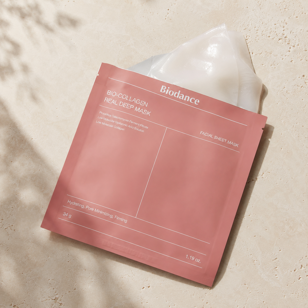 Biodance Bio-Collagen Real Deep Mask 34g shown with the translucent sheet mask partially removed from the pouch on warm travertine.