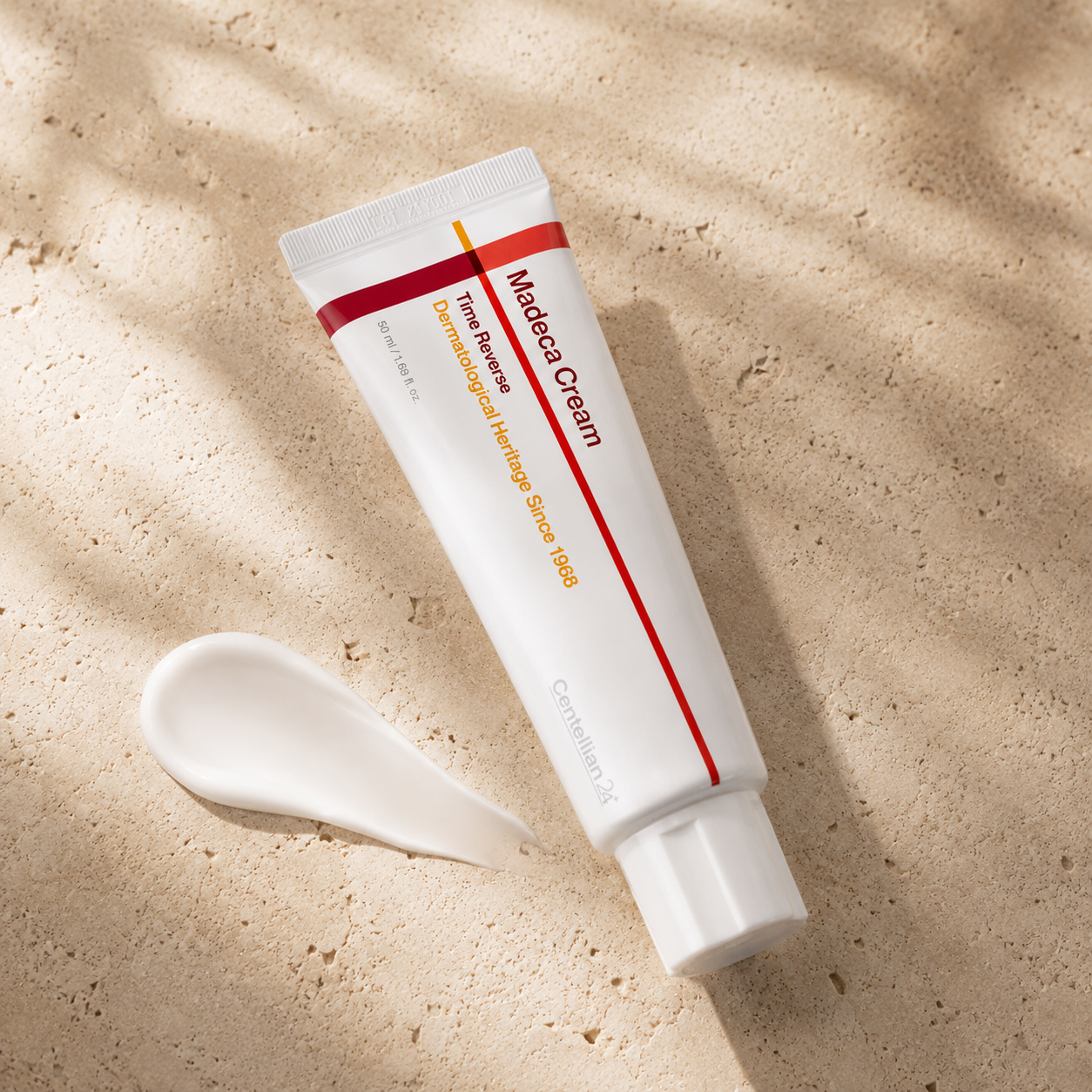 Centellian24 Madeca Cream Time Reverse 50ml placed beside a smooth white cream texture on warm travertine, highlighting its rich moisturizing formula.