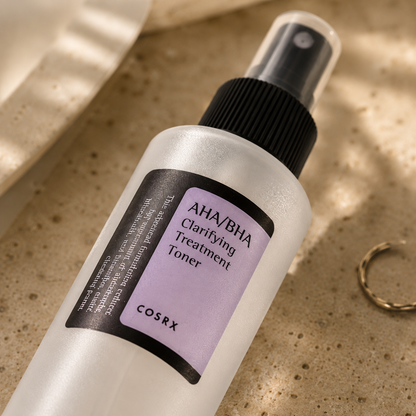 Macro close-up of the COSRX AHA/BHA Clarifying Treatment Toner bottle resting on warm beige travertine, highlighting the frosted bottle finish, fine mist spray, and label details with soft morning sunlight and a luxury Korean skincare editorial aesthetic.
