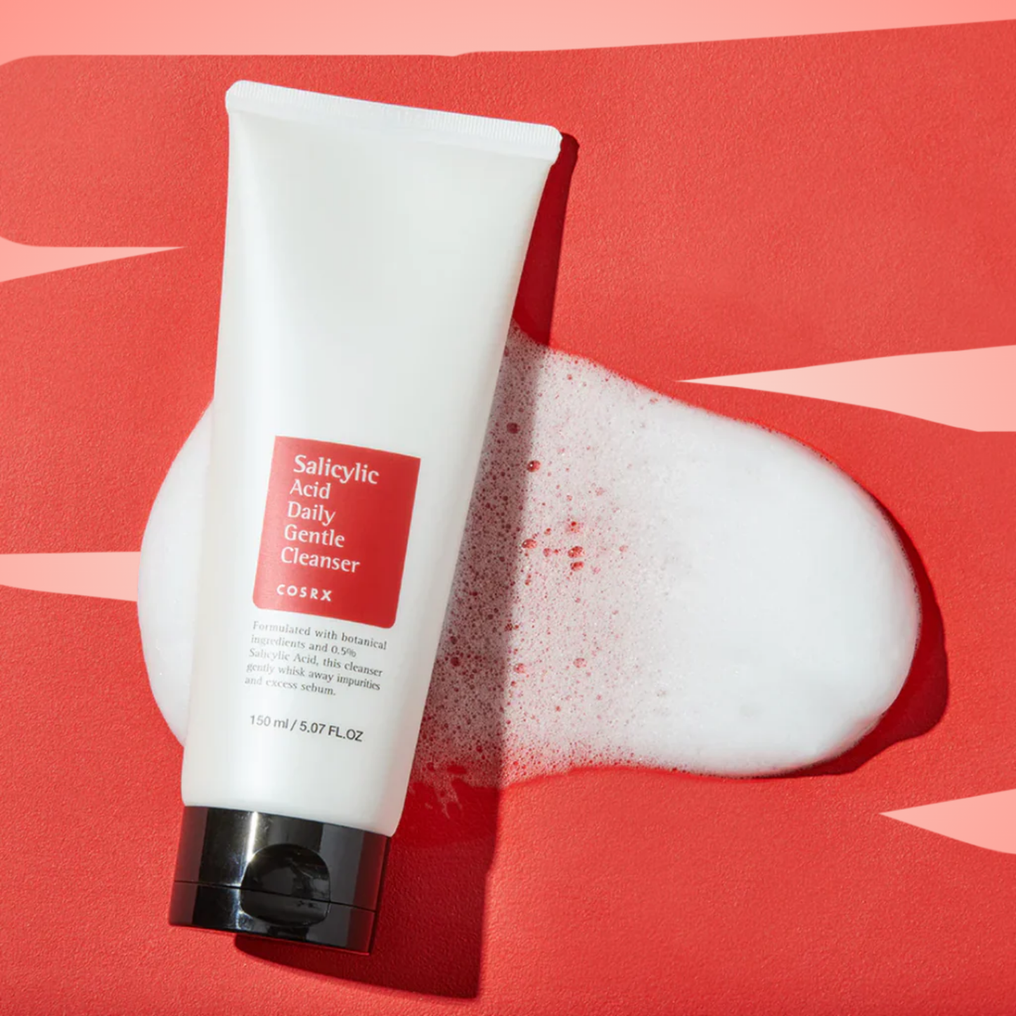COSRX Salicylic Acid Daily Gentle Cleanser flatlay on bold red backdrop with lather detail