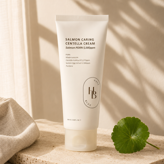 Heveblue Salmon Caring Centella Cream 100ml displayed upright on warm ivory travertine with soft morning sunlight and minimal botanical shadows in a premium Korean skincare hero photo.