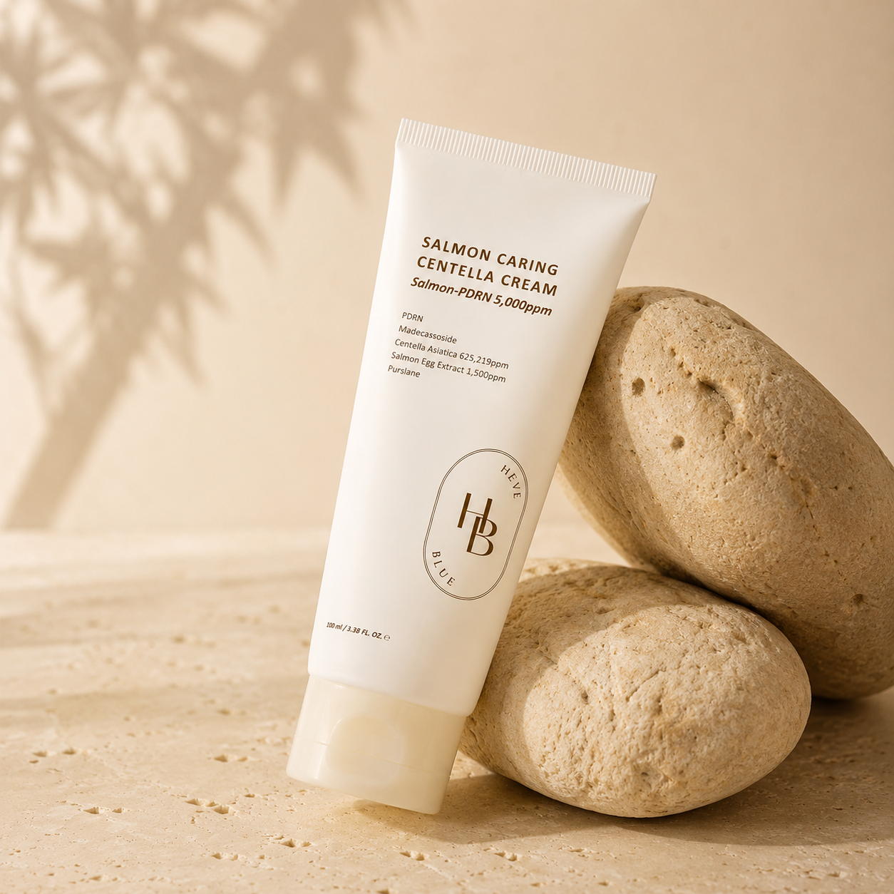 Heveblue Salmon Caring Centella Cream 100ml leaning naturally against textured stone on a warm beige surface in a calm luxury skincare editorial scene.