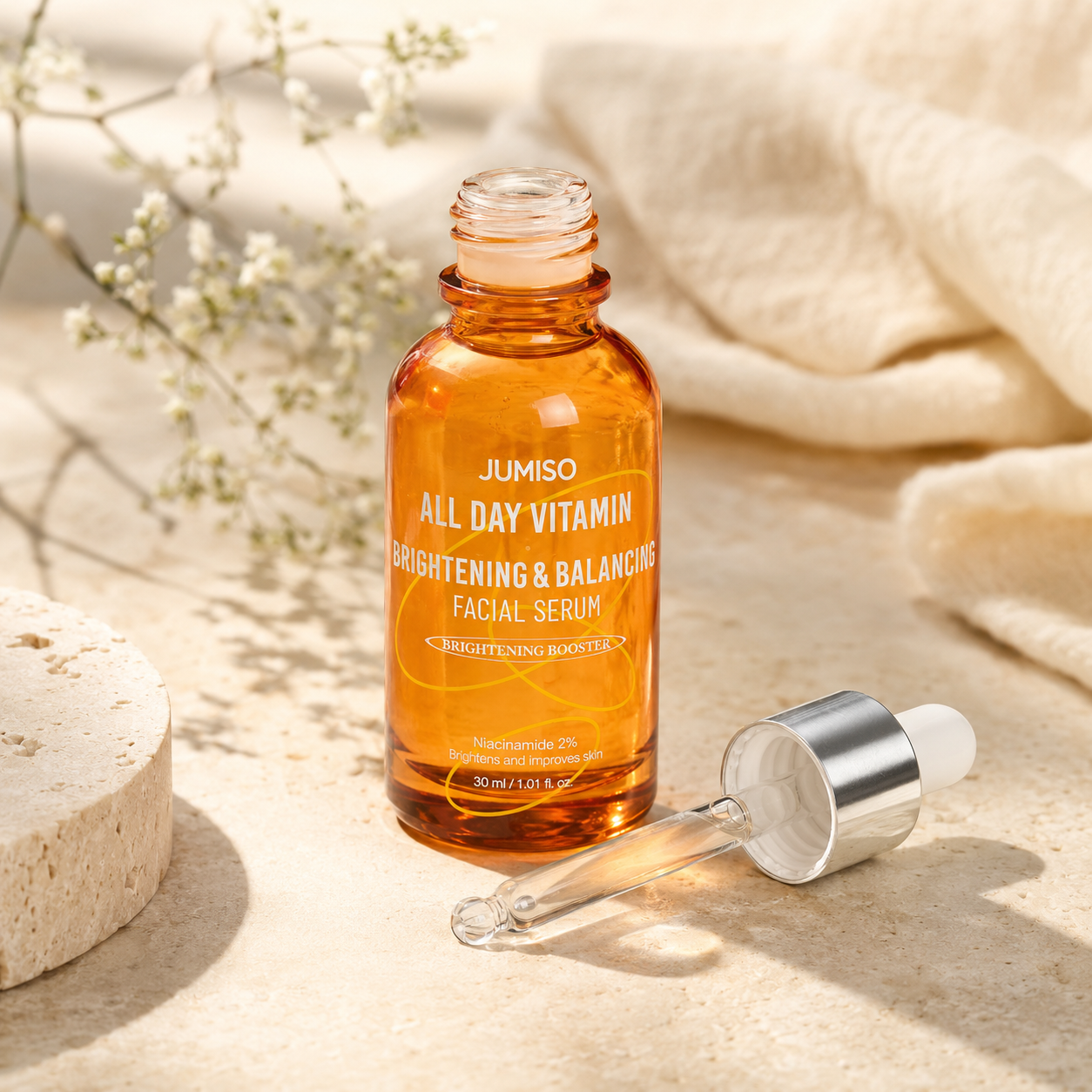 Open bottle of Jumiso All Day Vitamin Brightening & Balancing Facial Serum 30ml with glass dropper placed beside it on warm travertine in a premium skincare editorial scene.