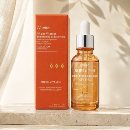 Jumiso All Day Vitamin Brightening & Balancing Facial Serum 30ml shown beside its orange product box on warm stone in soft natural light.