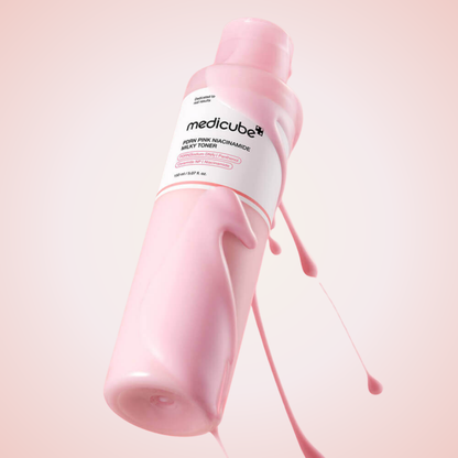 Medicube PDRN Pink Niacinamide Milky Toner tilted bottle with flowing texture – hydrating and radiance-boosting skincare