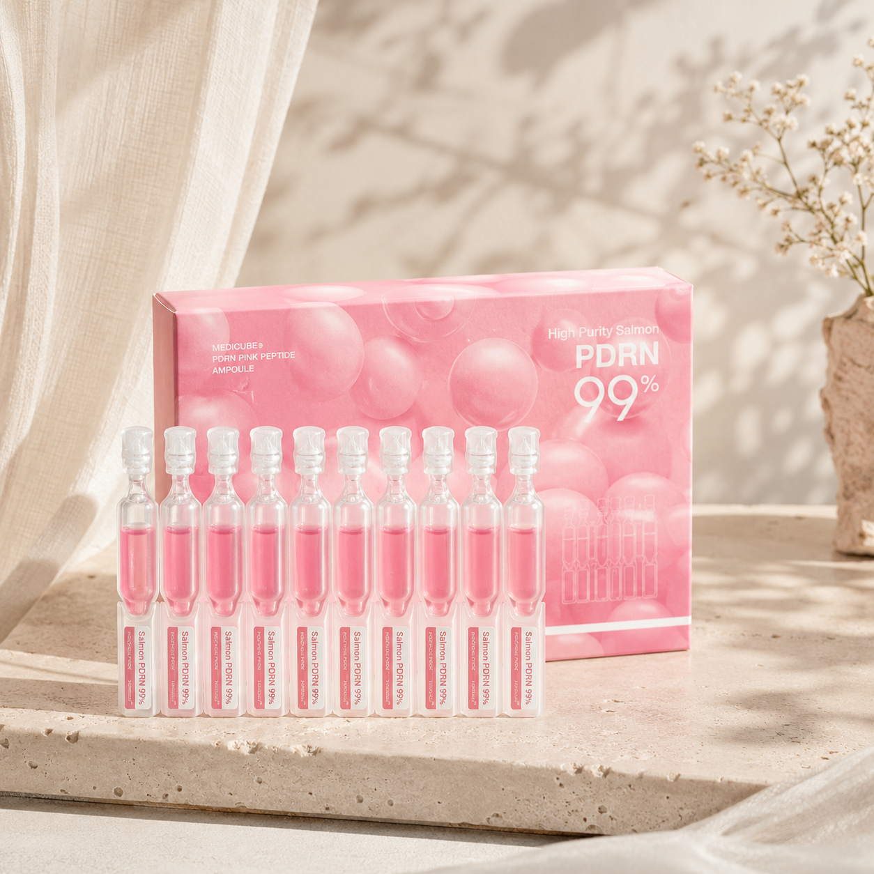 Medicube PDRN Pink Peptide Ampoule 99 displayed with its pink product box on warm travertine in a premium Korean skincare hero photo.