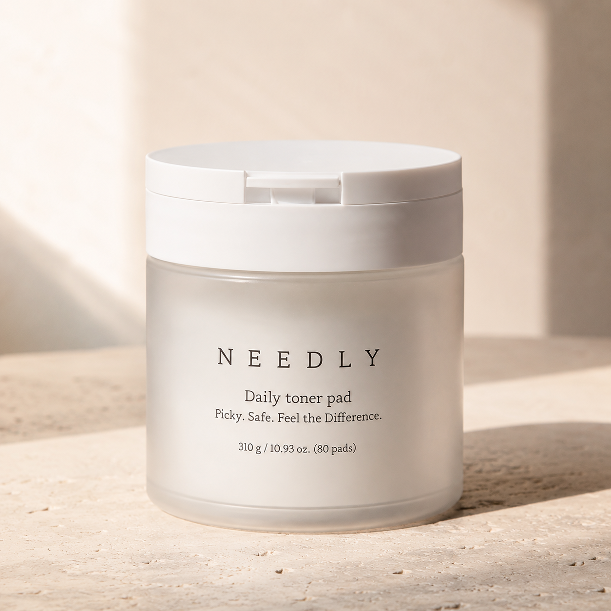 Needly Daily Toner Pad 310g 80 pads displayed on warm travertine with soft morning sunlight 