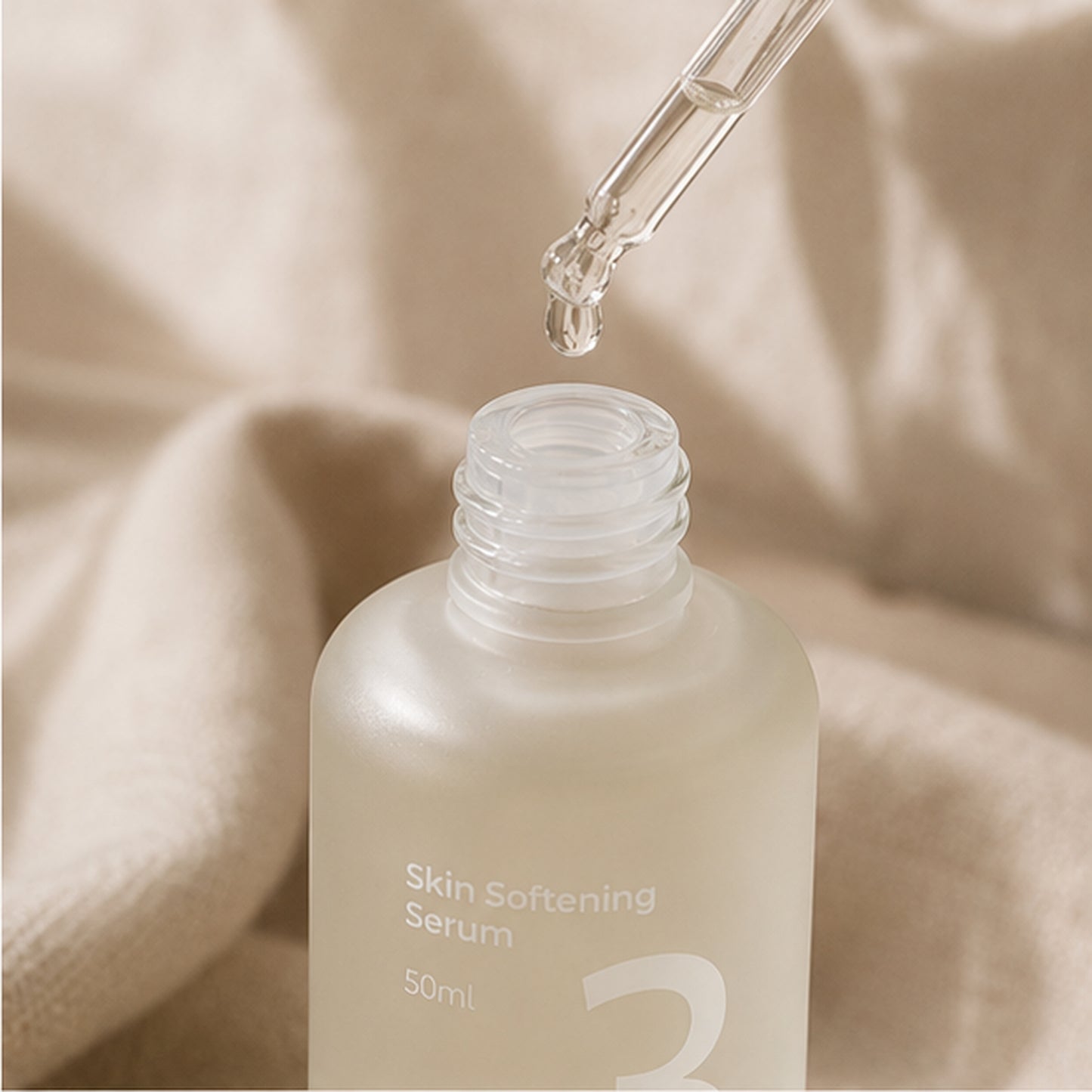 Numbuzin No.3 Skin Softening Serum 50ml shown on textured travertine with soft natural light, highlighting the frosted bottle and minimal white packaging.