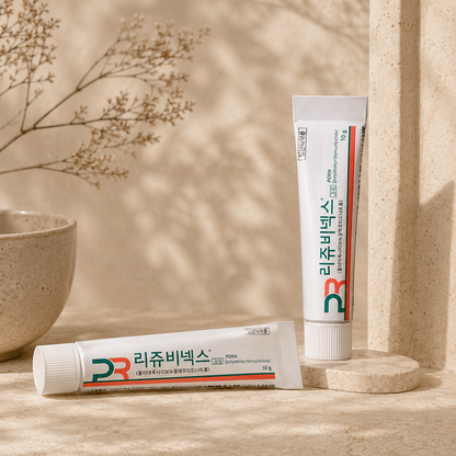 Rejuvenex PDRN Skin Repair Cream 10g in an editorial skincare scene, displayed on warm beige travertine stone with soft morning sunlight, delicate botanical shadows, and a minimalist Korean skincare aesthetic.