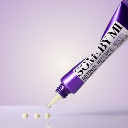 Close-up of SOME BY MI Retinol Intense Eye Cream tube and drops of product on light surface