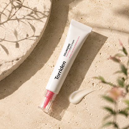 Torriden Cellmazing Firming Eye Cream 30ml placed beside a smooth cream texture on warm travertine, highlighting its firming eye care formula.