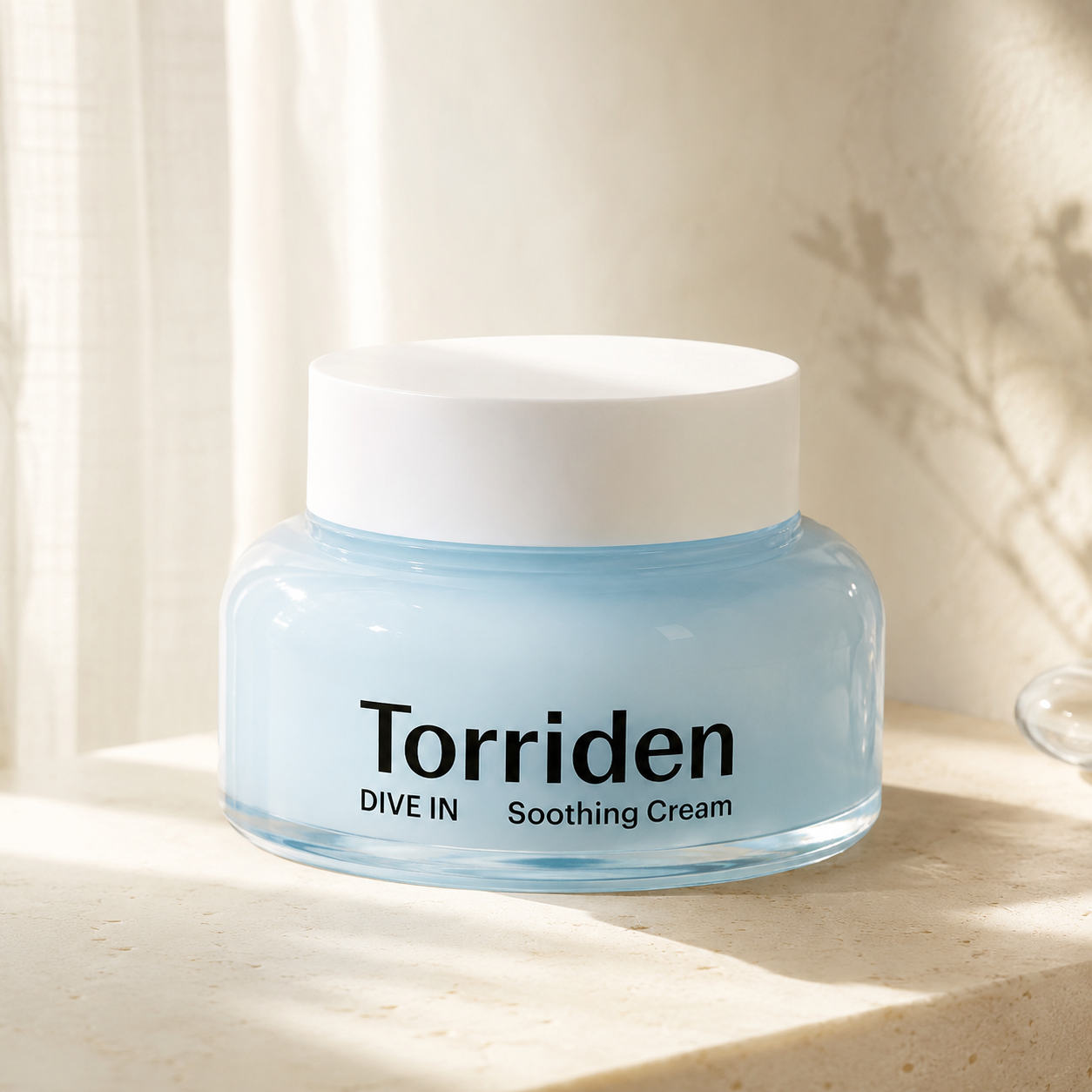 Torriden Dive-In Hyaluronic Acid Soothing Cream 100ml displayed on warm travertine with soft morning light in a premium Korean skincare hero photo.